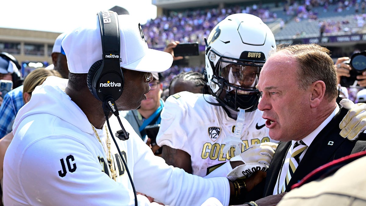 Deion Sanders shakes hands with Colorado athletic director Rick George
